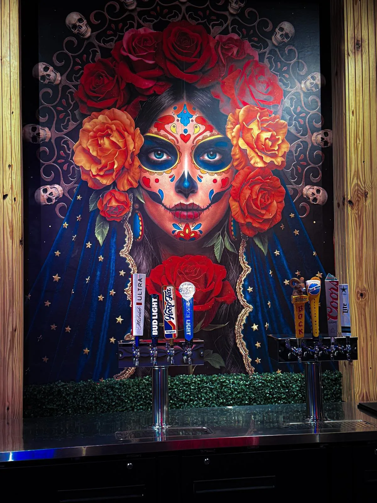 Colorful Catrina mural with red roses behind the beer taps at the Jalapeños cantina
